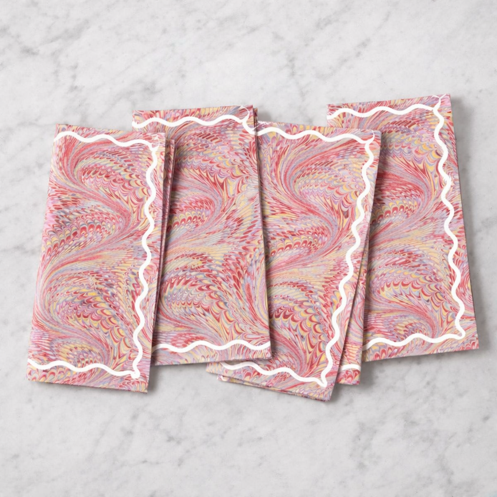 Set of four marbled patterned napkins on a marble surface